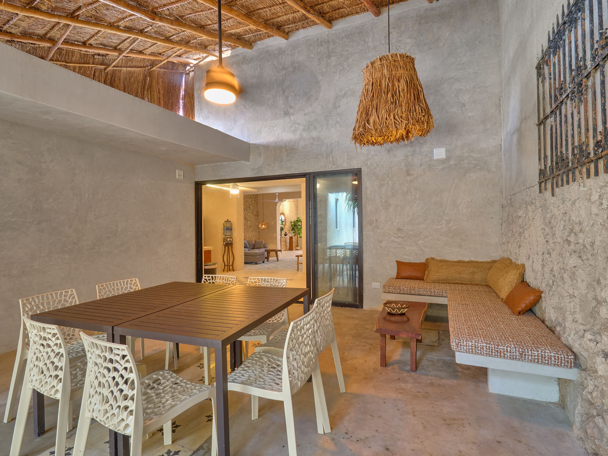 Rustic indoor dining and lounge area with wooden furniture and woven ceiling.