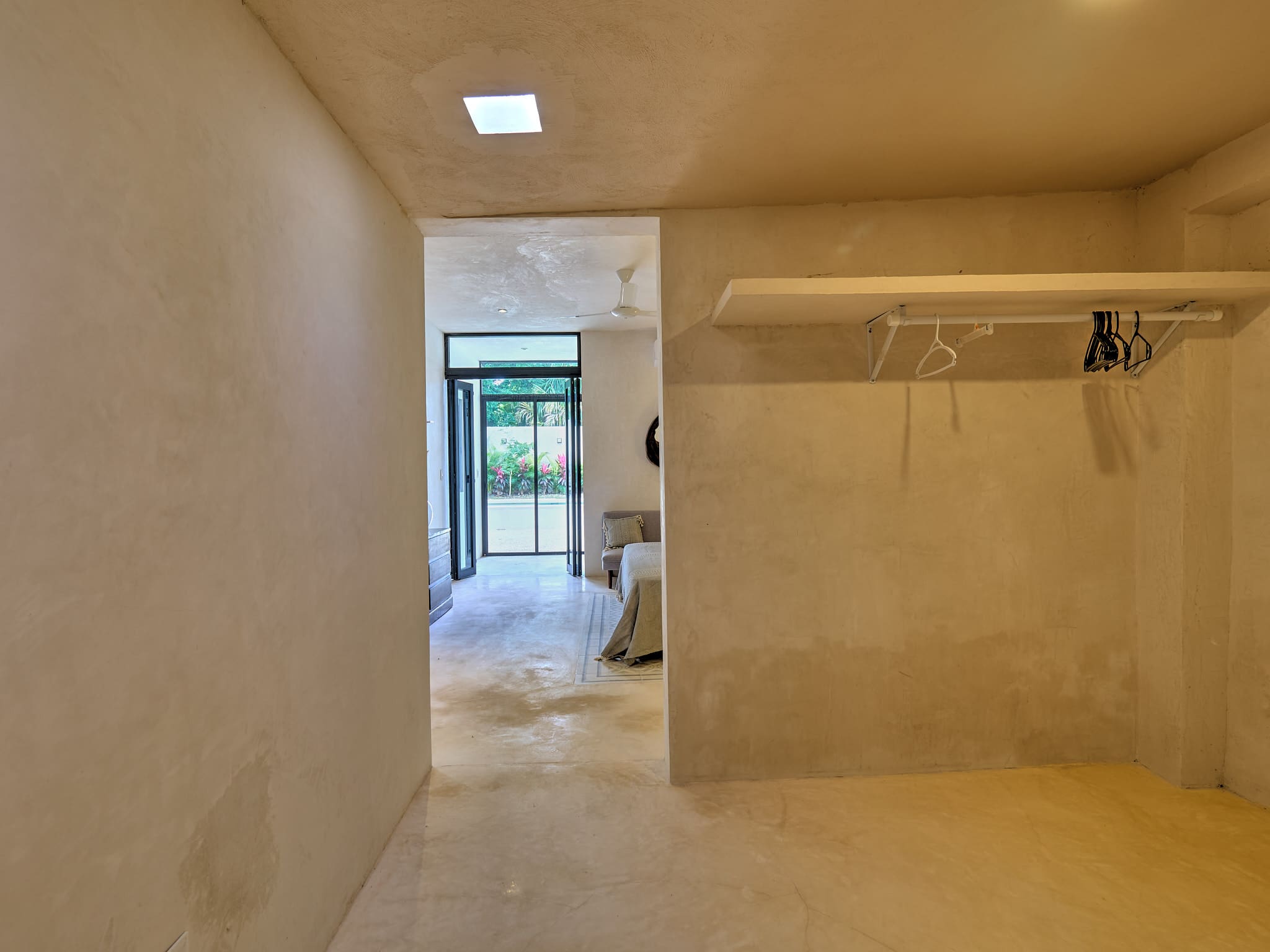 Empty beige hallway leading to a bright room with glass doors.