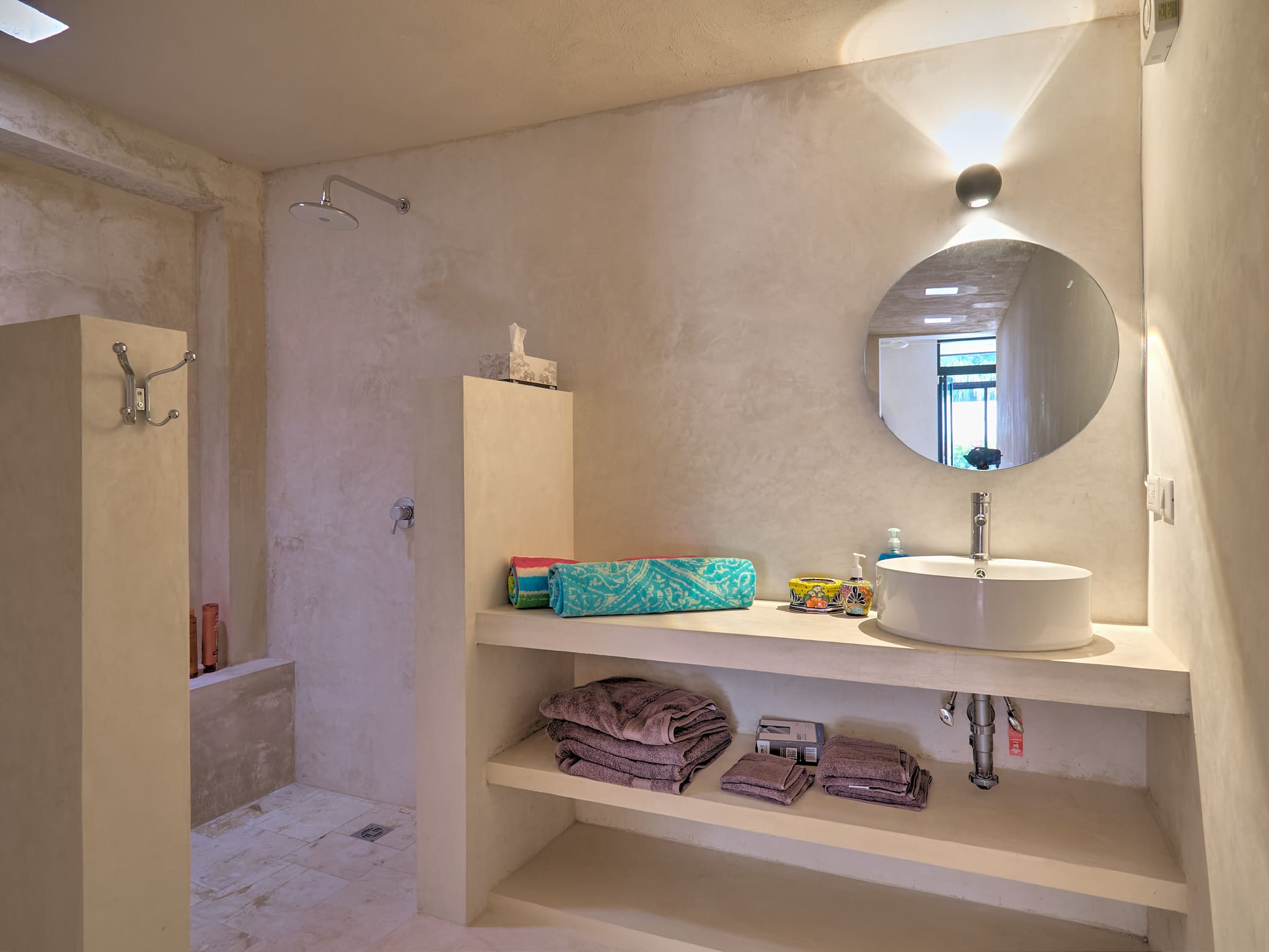 Minimalist bathroom with built-in shelves and round mirror.