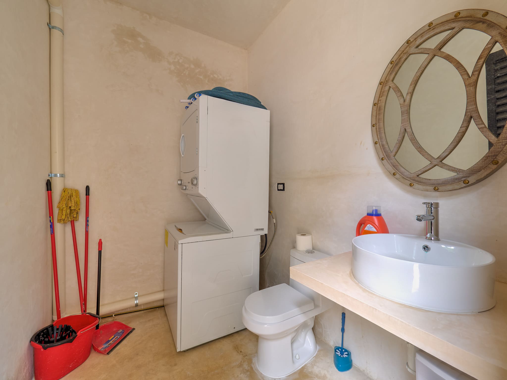 Small bathroom with stacked washer and dryer, toilet, and sink.