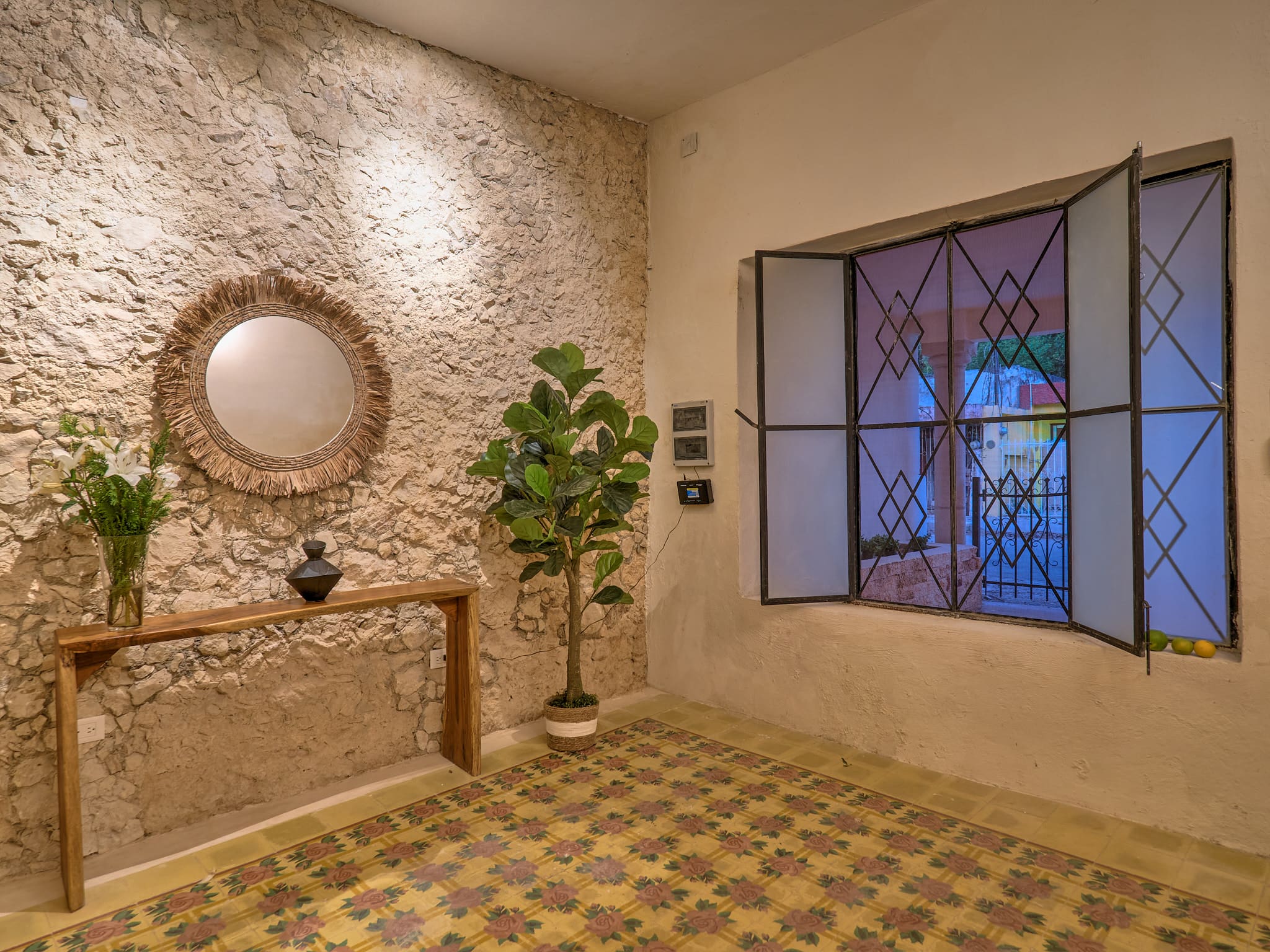 Cozy corner with rustic stone wall, round mirror, and window.