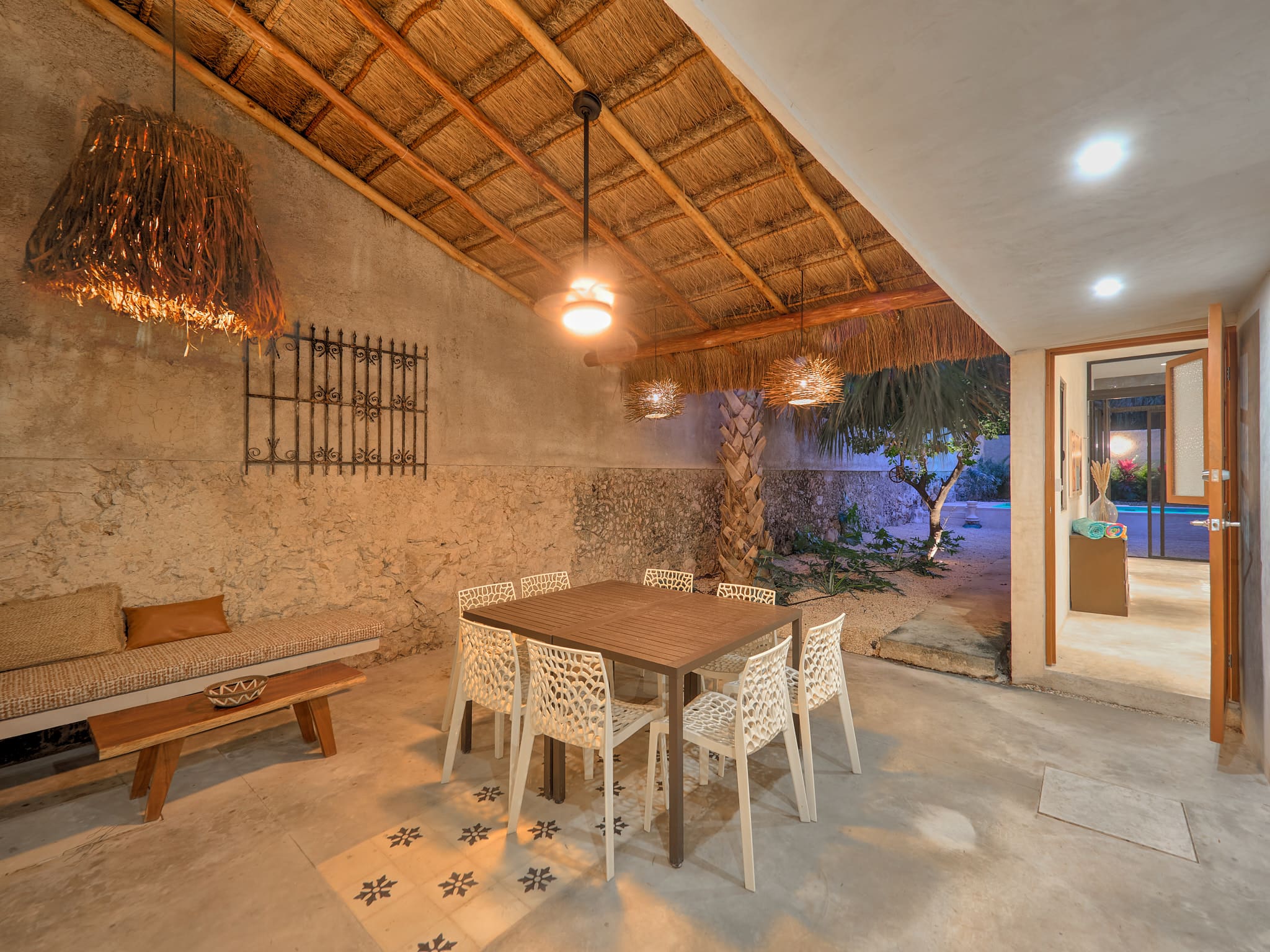 Cozy outdoor dining area with rustic thatched roof and warm lighting.