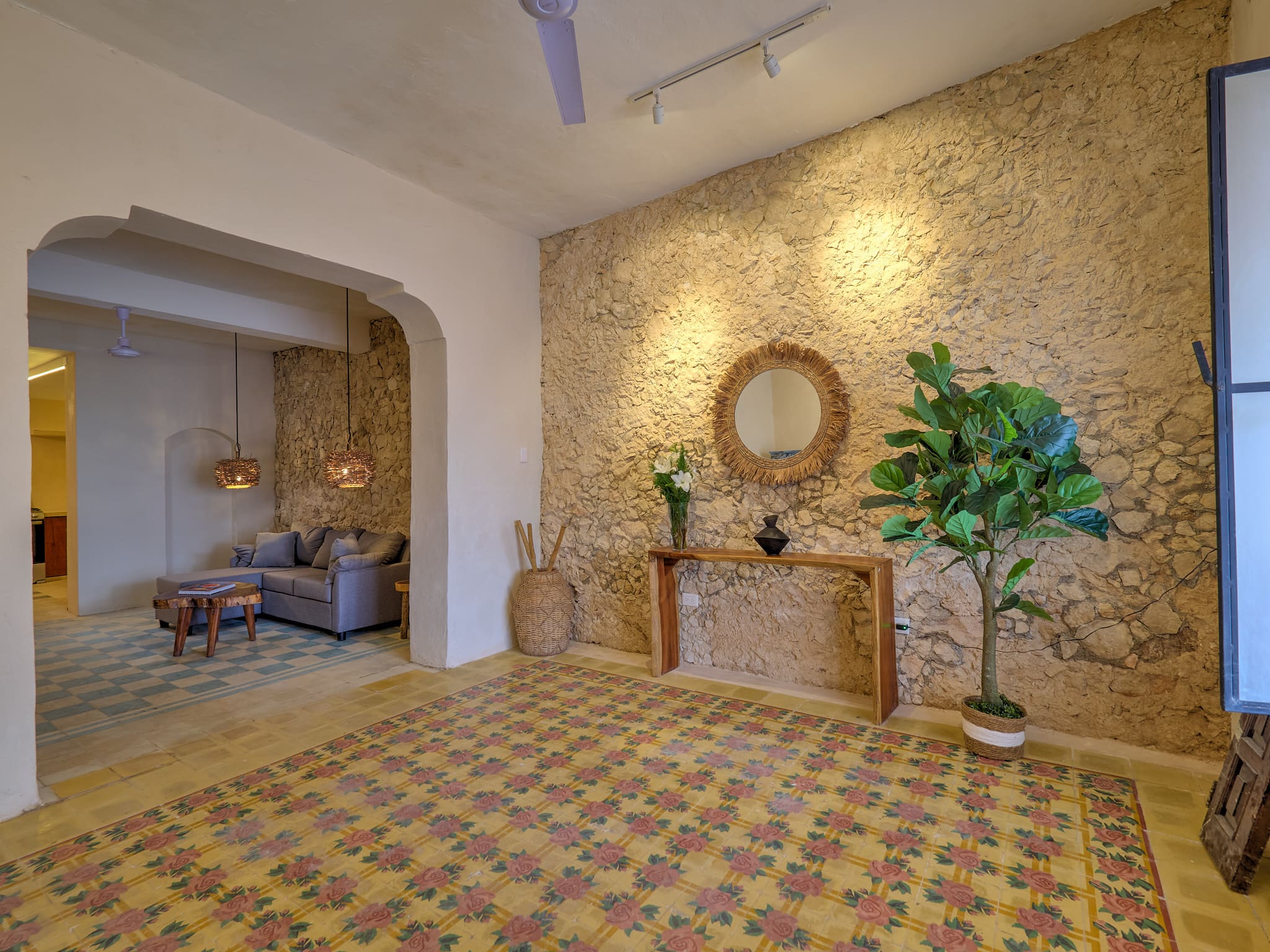 Cozy living room with warm stone wall and patterned tile floor.