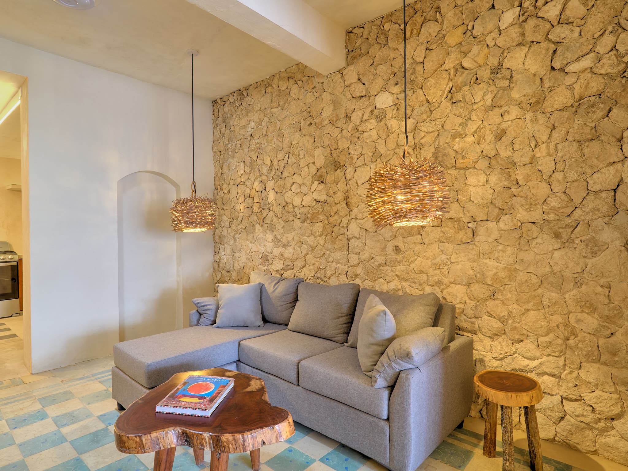 Cozy living room with a gray sofa and rustic stone wall.