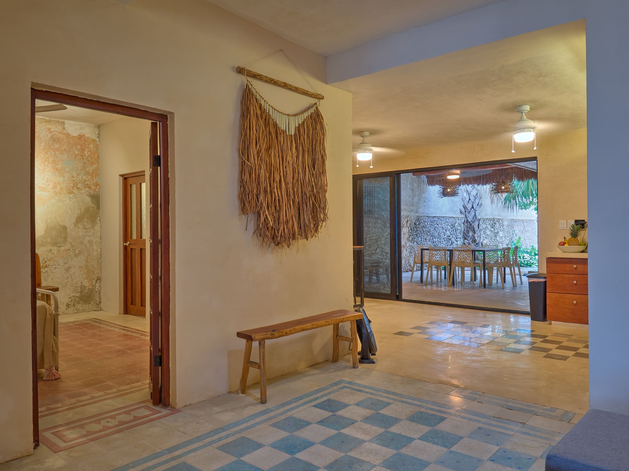 Cozy living space with woven wall art and wooden bench.