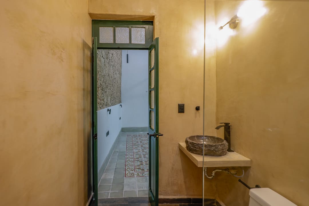 Narrow bathroom with vintage sink and partially tiled walls.