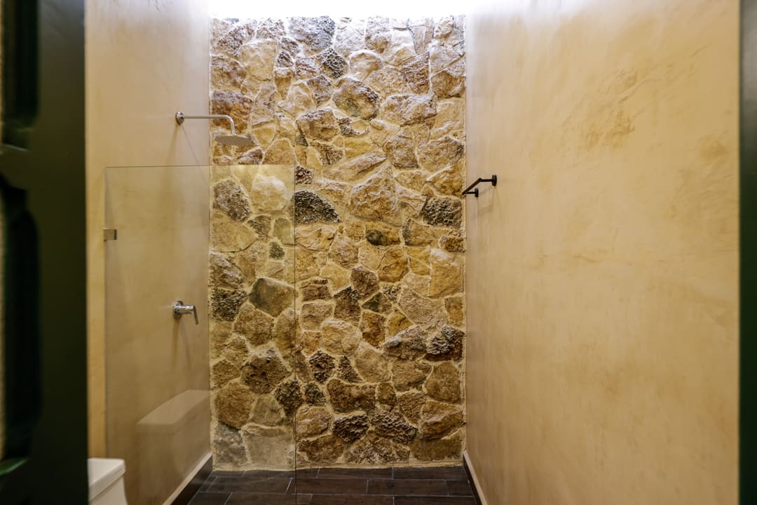 Indoor shower with stone accent wall and beige tiles.
