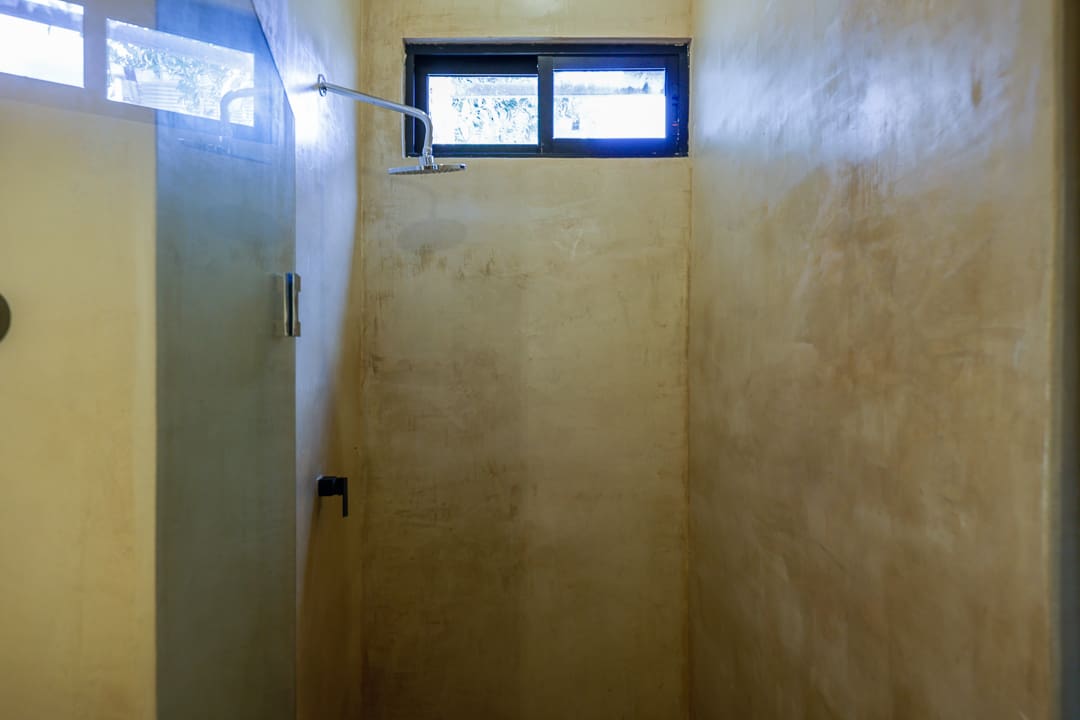 Small, dimly lit shower stall with frosted window and tiled walls.