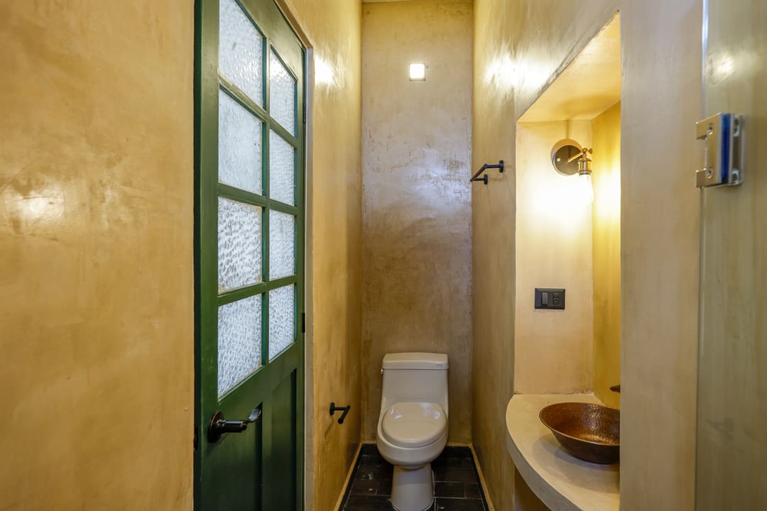 Compact bathroom with a toilet and sink under warm lighting.