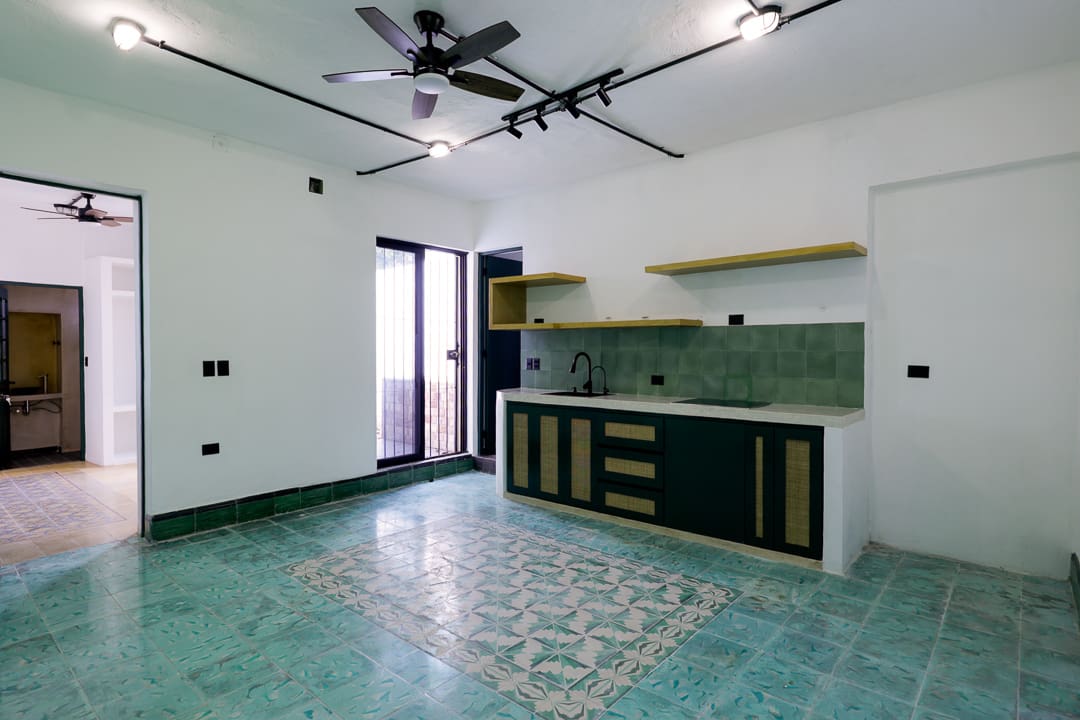 Modern kitchen with teal floor tiles and black cabinetry.
