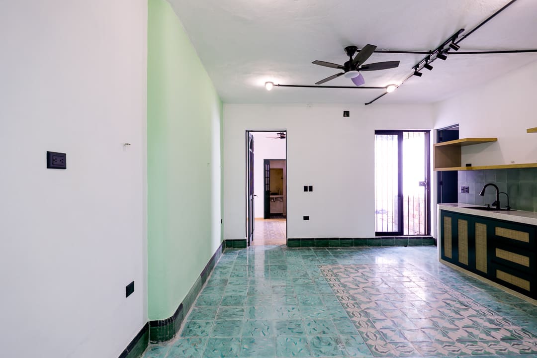 Empty room with green tiled floor and ceiling fans.