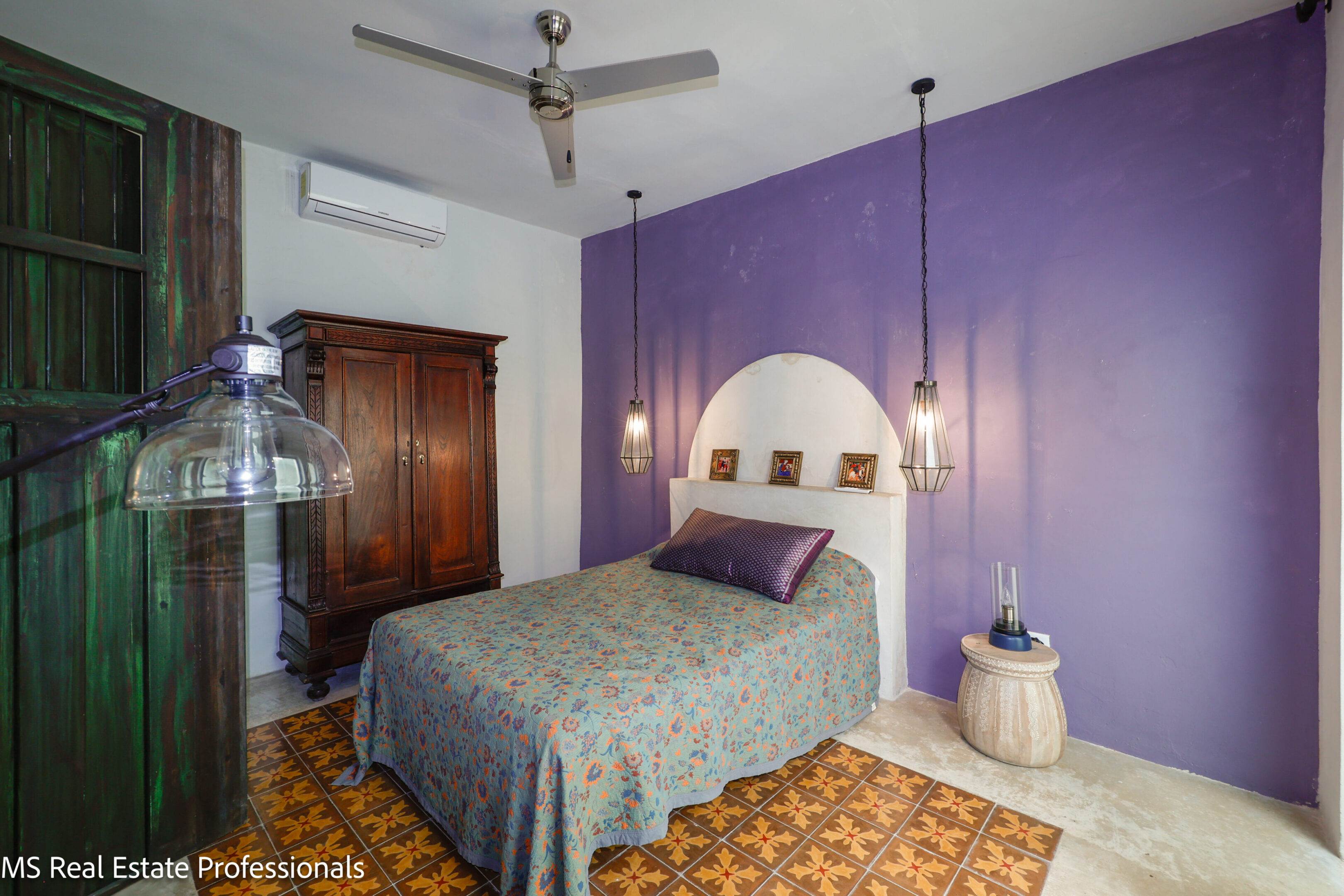Cozy bedroom with a purple accent wall and vintage wooden wardrobe.