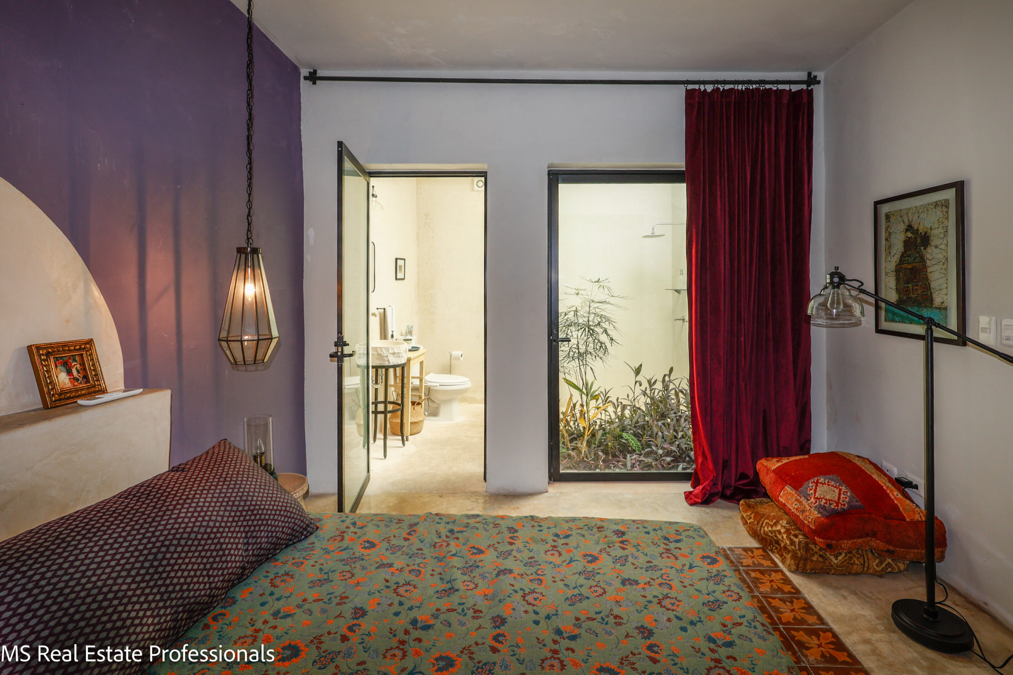 Cozy bedroom with purple walls, patterned bedding, and warm lighting.