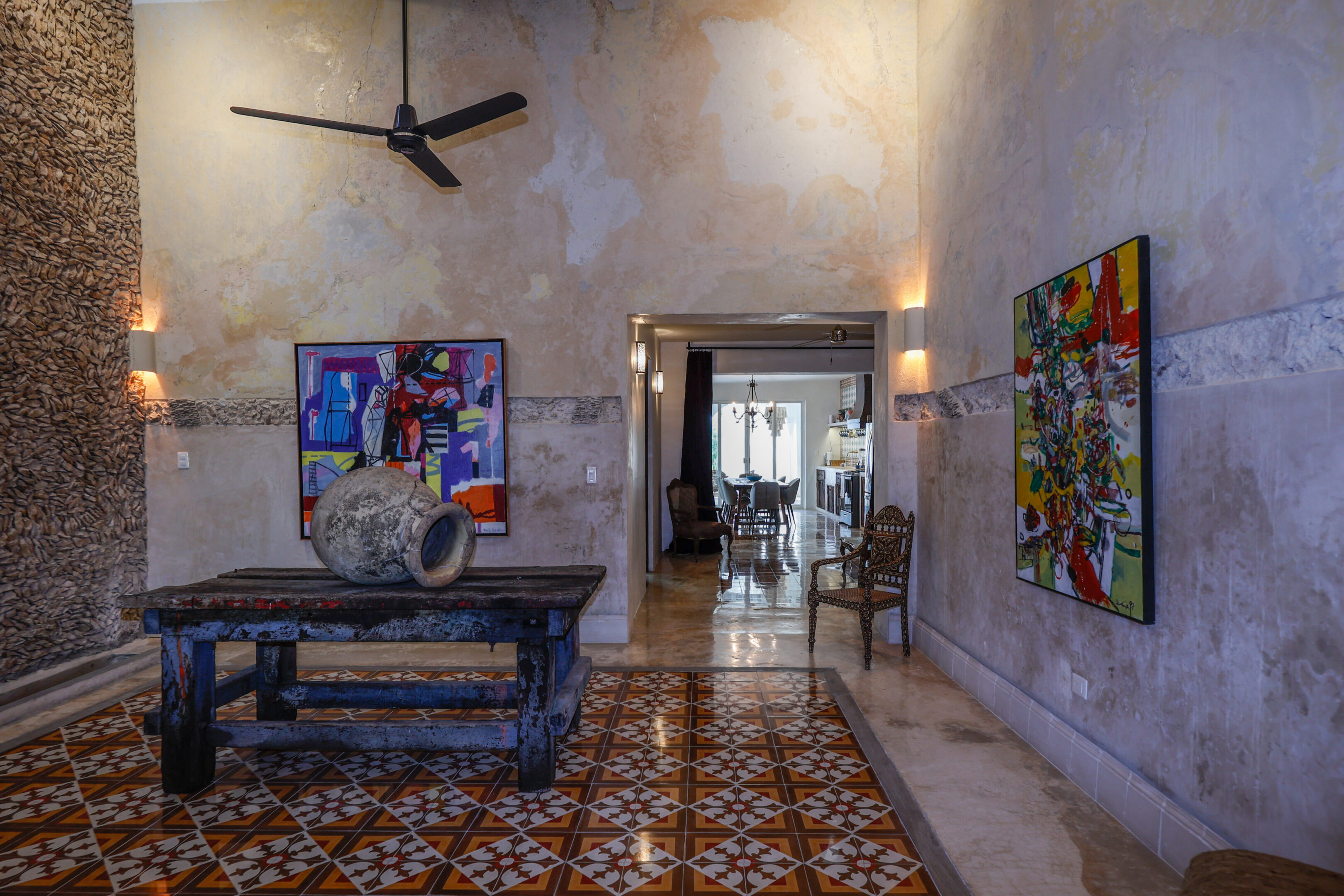 Rustic room with patterned floor tiles and eclectic artwork.