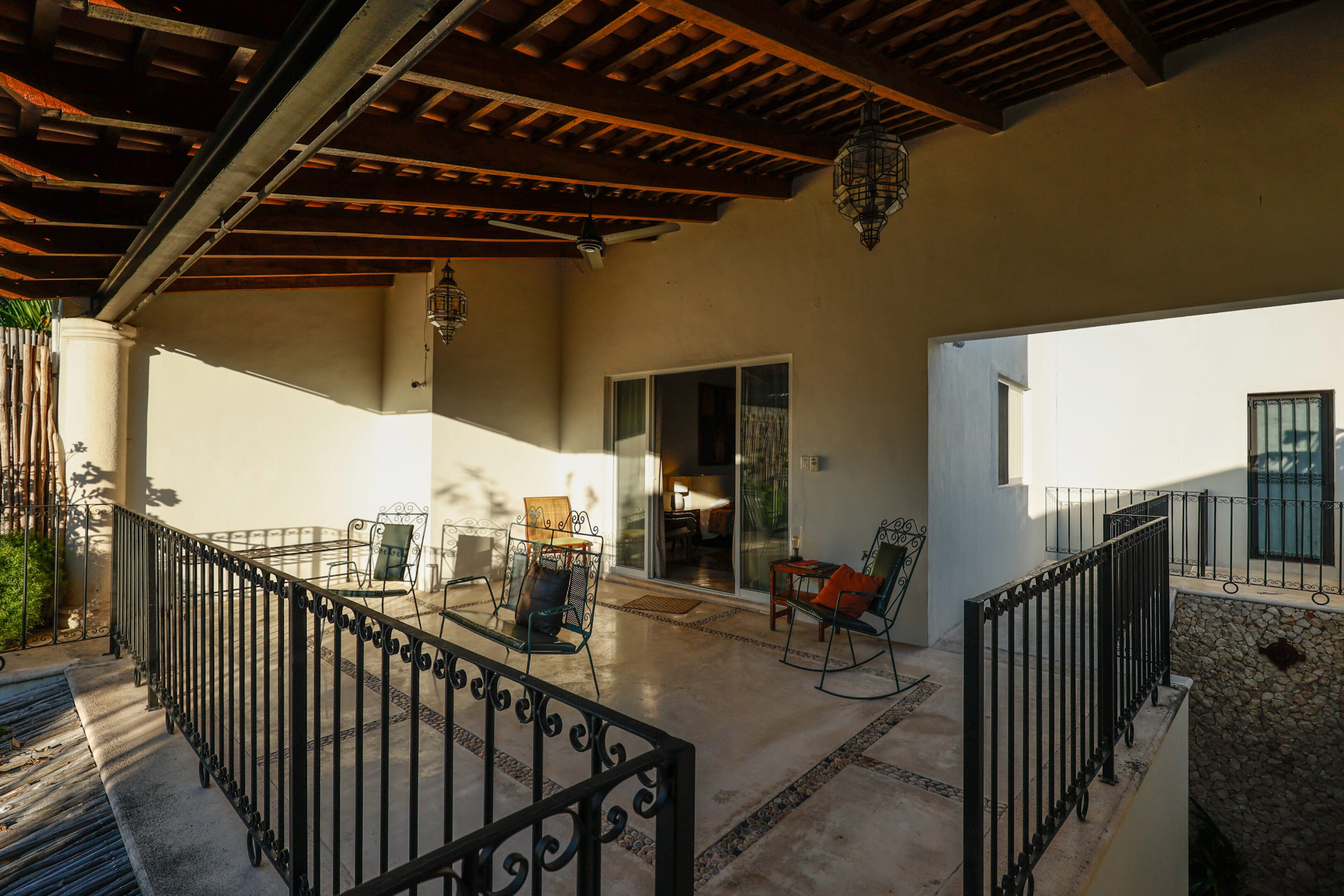 Sunlit rustic terrace with vintage furniture and wooden ceiling.