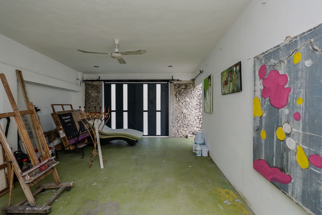 Empty room with green floor and wall art, featuring black window blinds and ceiling fan.