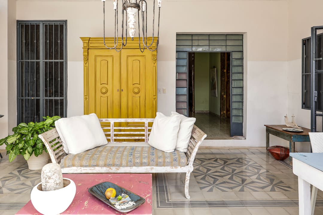 Cozy outdoor seating area with white cushioned chairs and a yellow cabinet.
