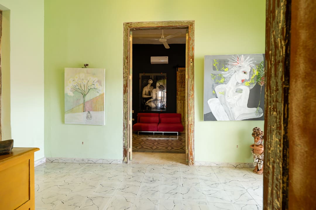 Open doorway revealing a cozy interior with wall art and red cushions.