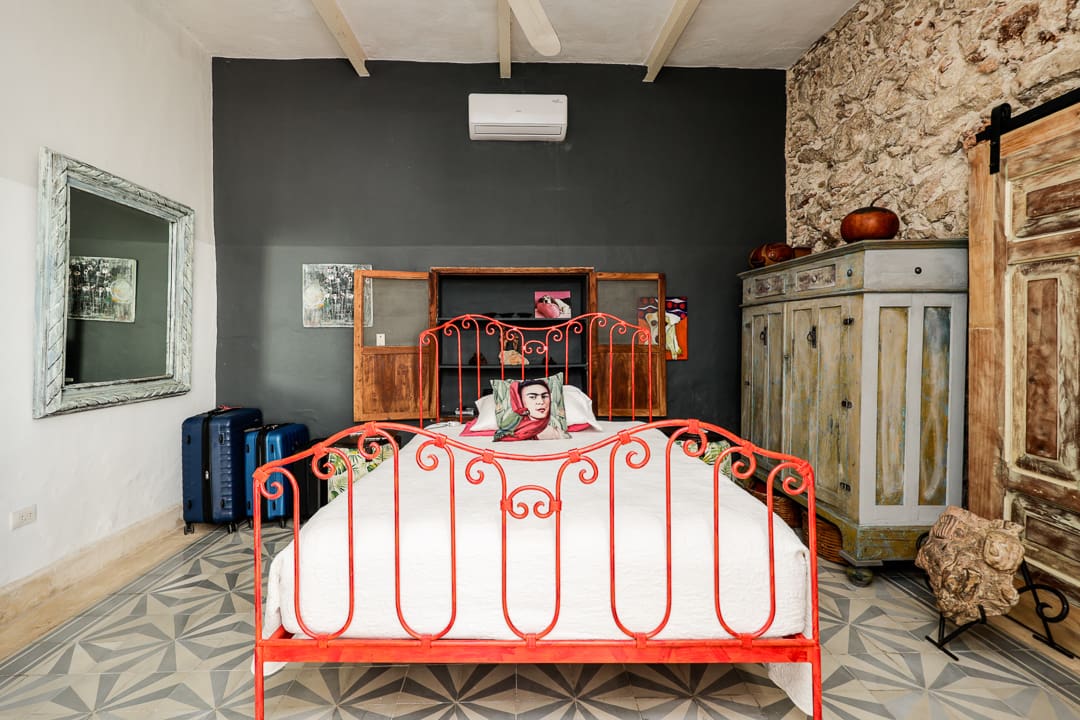 Cozy bedroom with a red wrought iron bed and rustic decor.