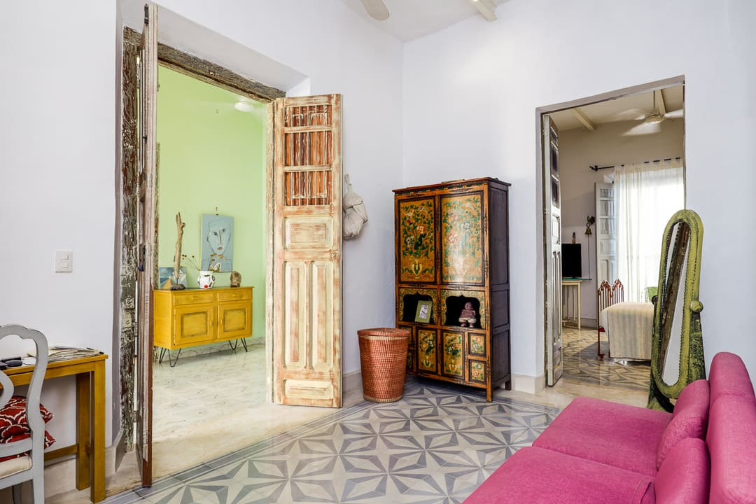 Bright, eclectic living space with vintage furniture and patterned floors.