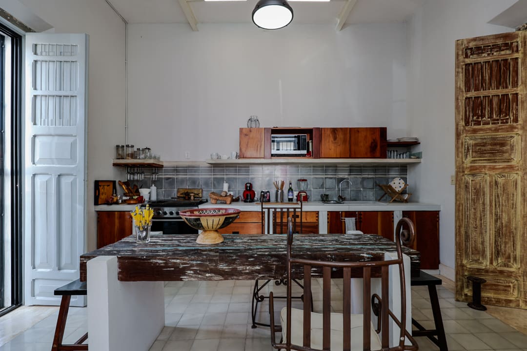 Rustic kitchen with open shelves, wooden cabinets, and a marble countertop island.