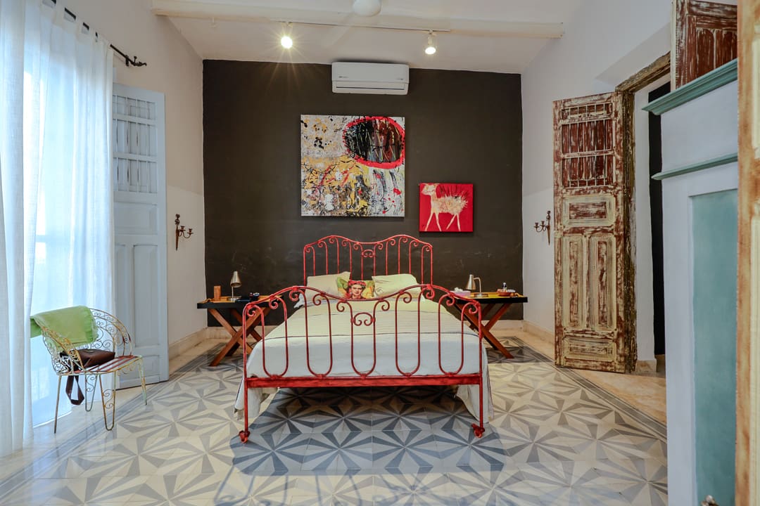 Cozy bedroom with a vintage red metal bed and artistic decor.