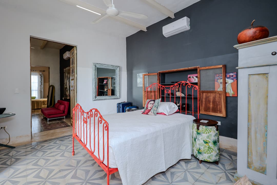 Cozy bedroom with red metal bed frame and stylish decor.