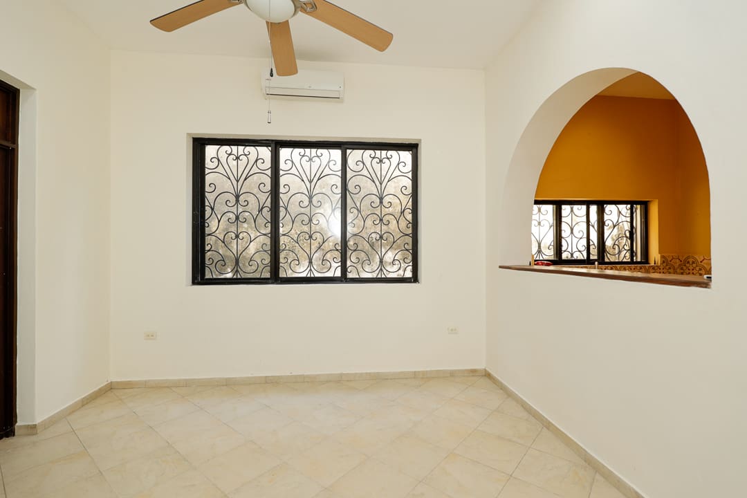 Empty room with a ceiling fan and large windows overlooking trees.