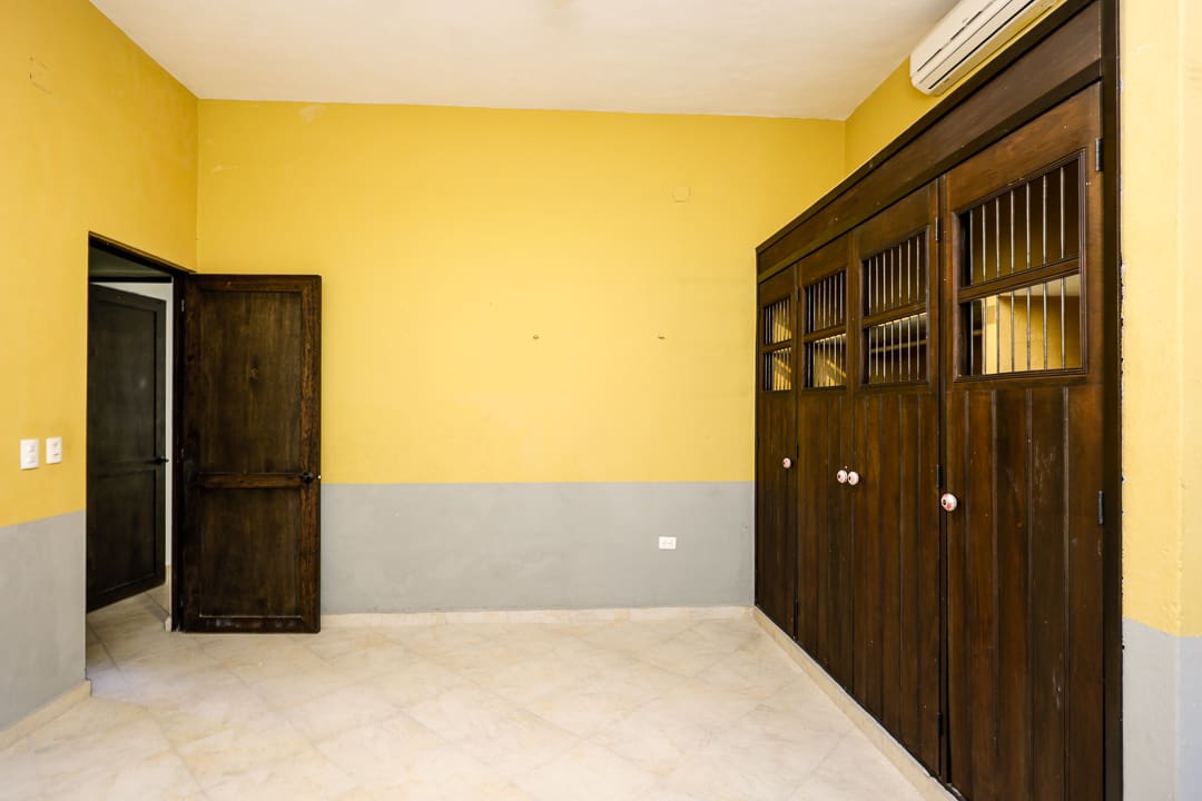 Empty room with yellow and gray walls, wooden cabinets, and a door.