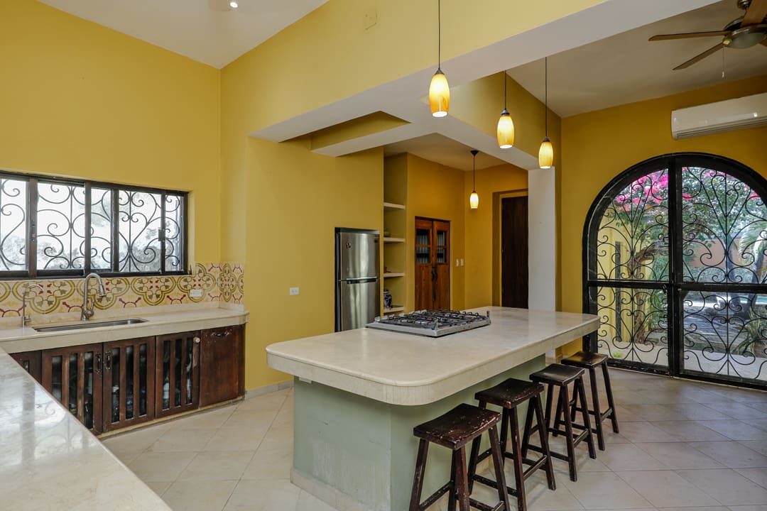 Modern kitchen with yellow walls and a large island with bar stools.