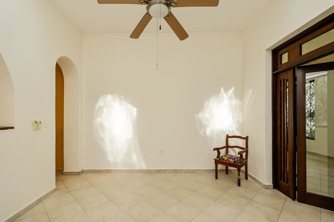 Empty room with two ghostly light figures and a wooden chair.