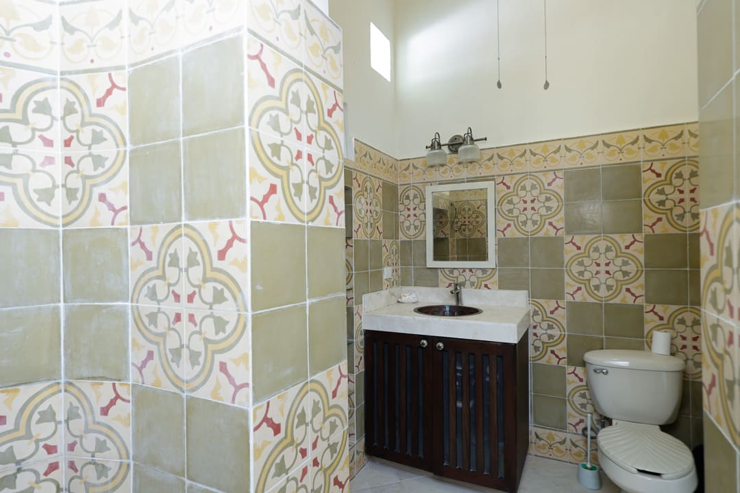 Bathroom with patterned tile walls and a dark wood vanity.