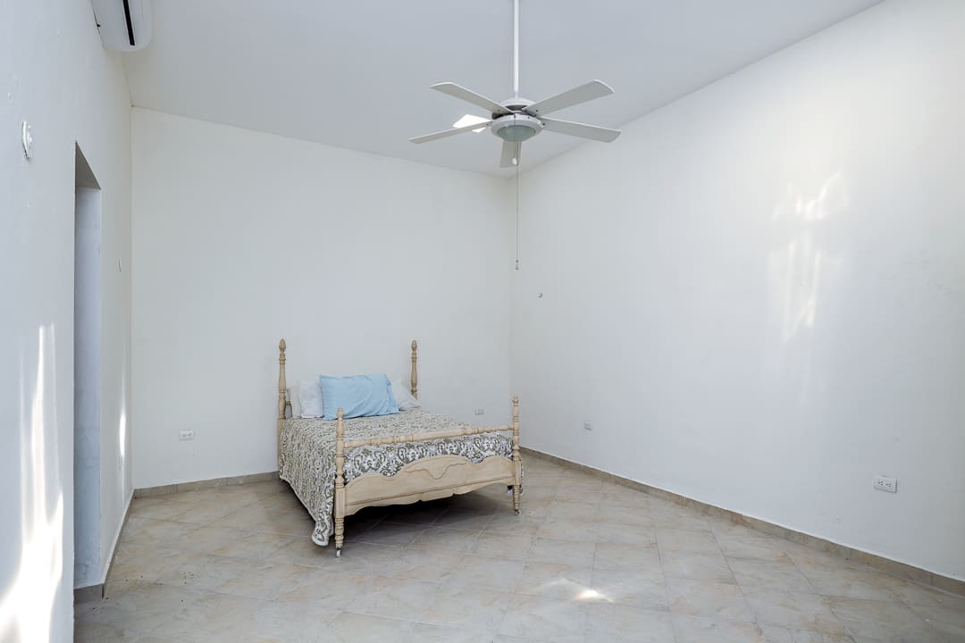 A simple bedroom with a single bed and ceiling fan.
