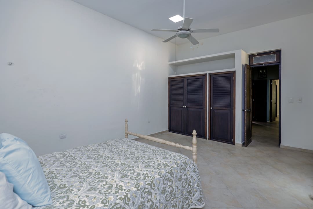 Simple bedroom with a ceiling fan and closed dark wardrobes.