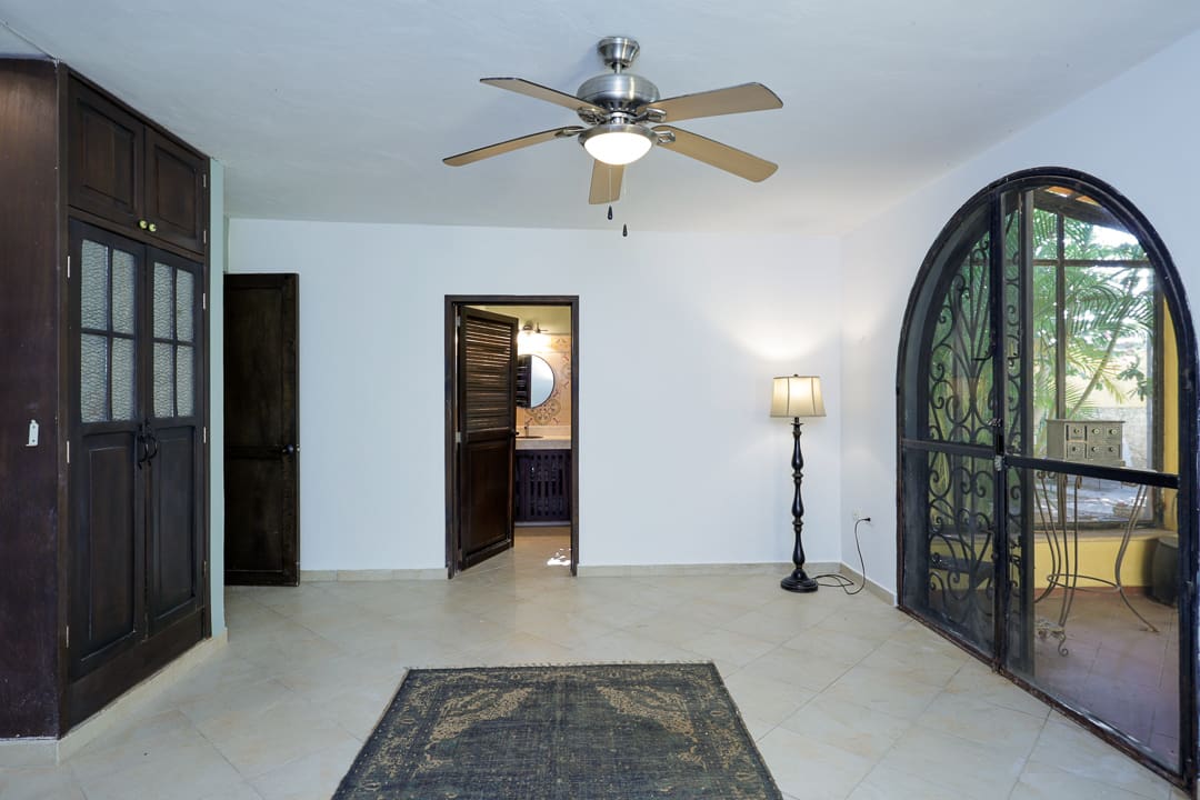 Minimalist room with a ceiling fan, carpet, and arched doors.