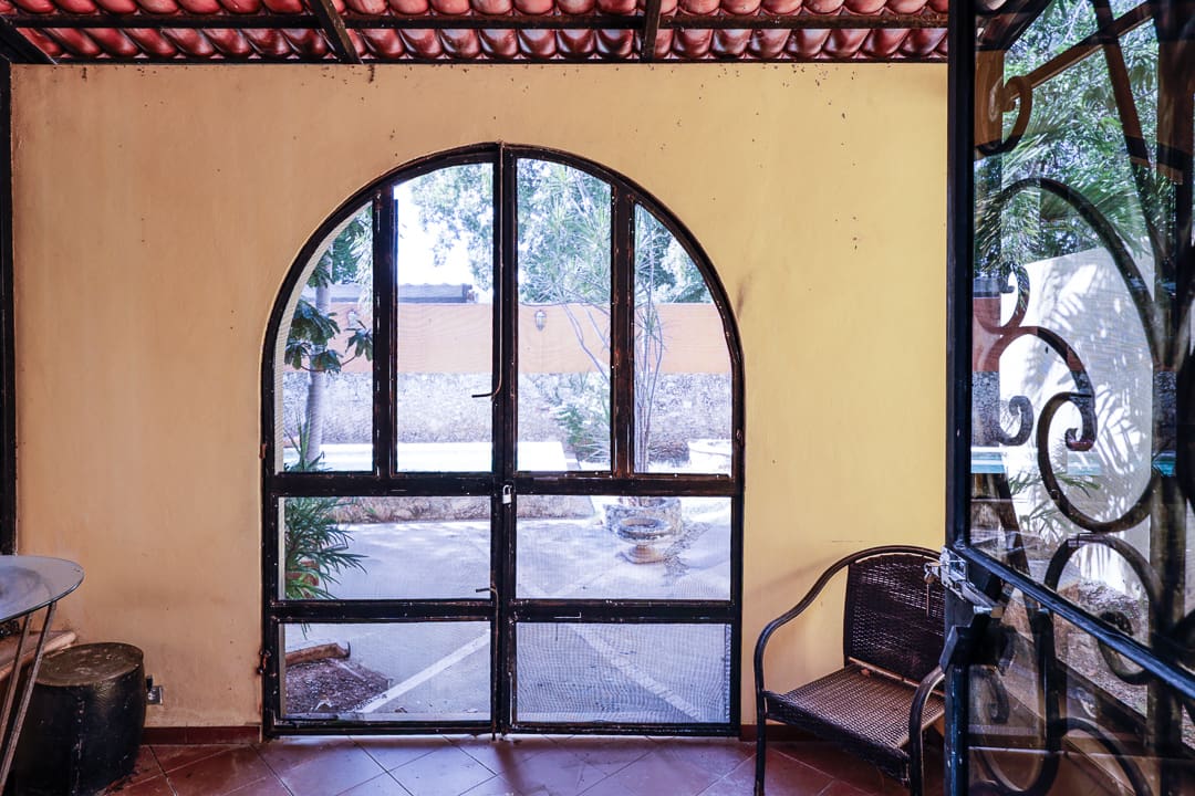A rustic arched glass door with a view of an outdoor garden.