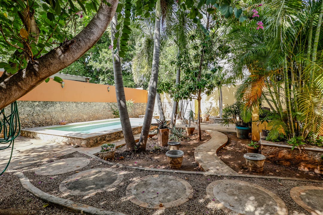 Shaded garden patio with stone flooring and a swimming pool.