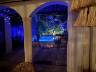 Nighttime pool area illuminated with blue and green lights viewed through an archway.