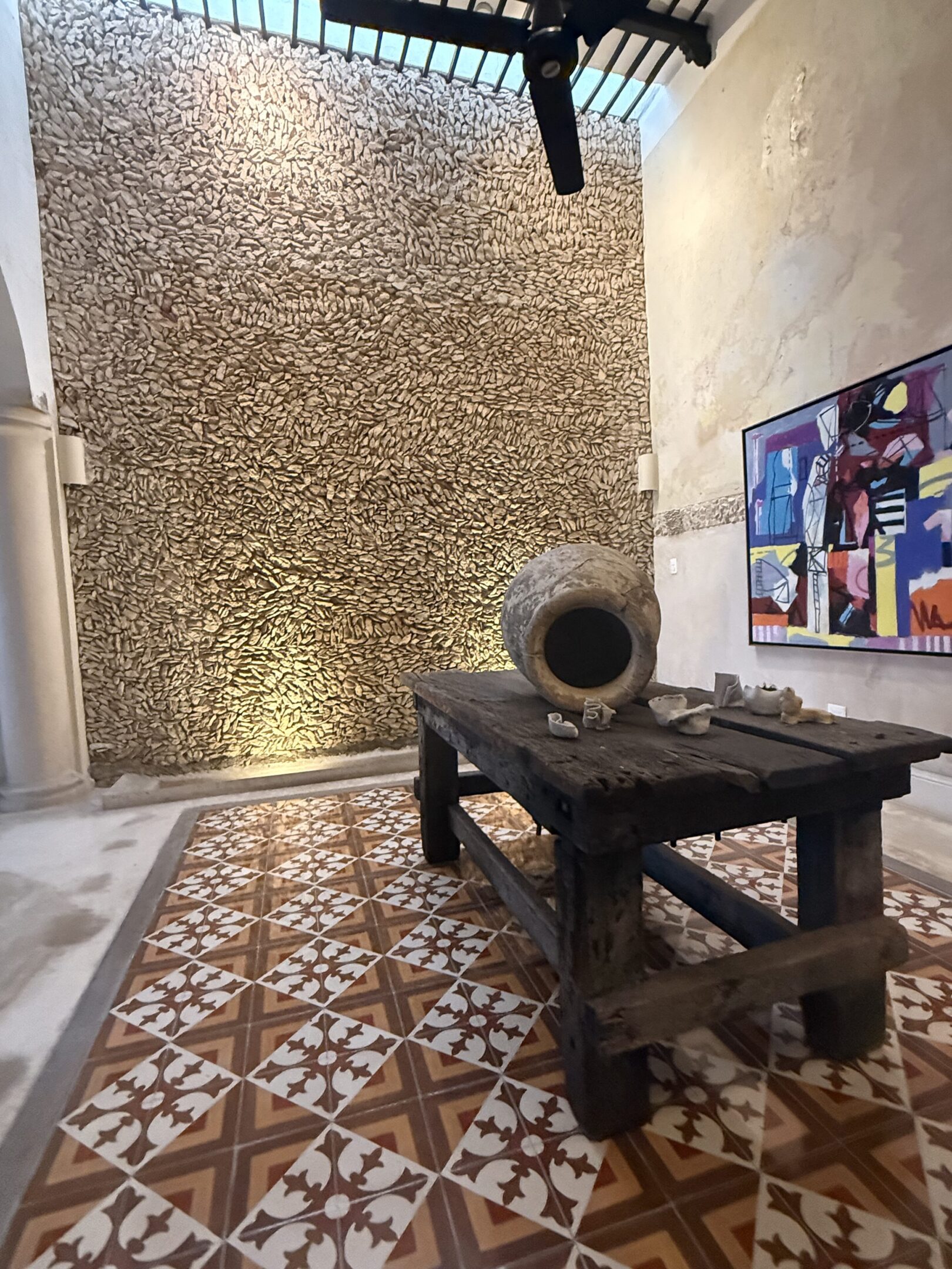 Rustic wooden table with a large clay pot against a textured stone wall.