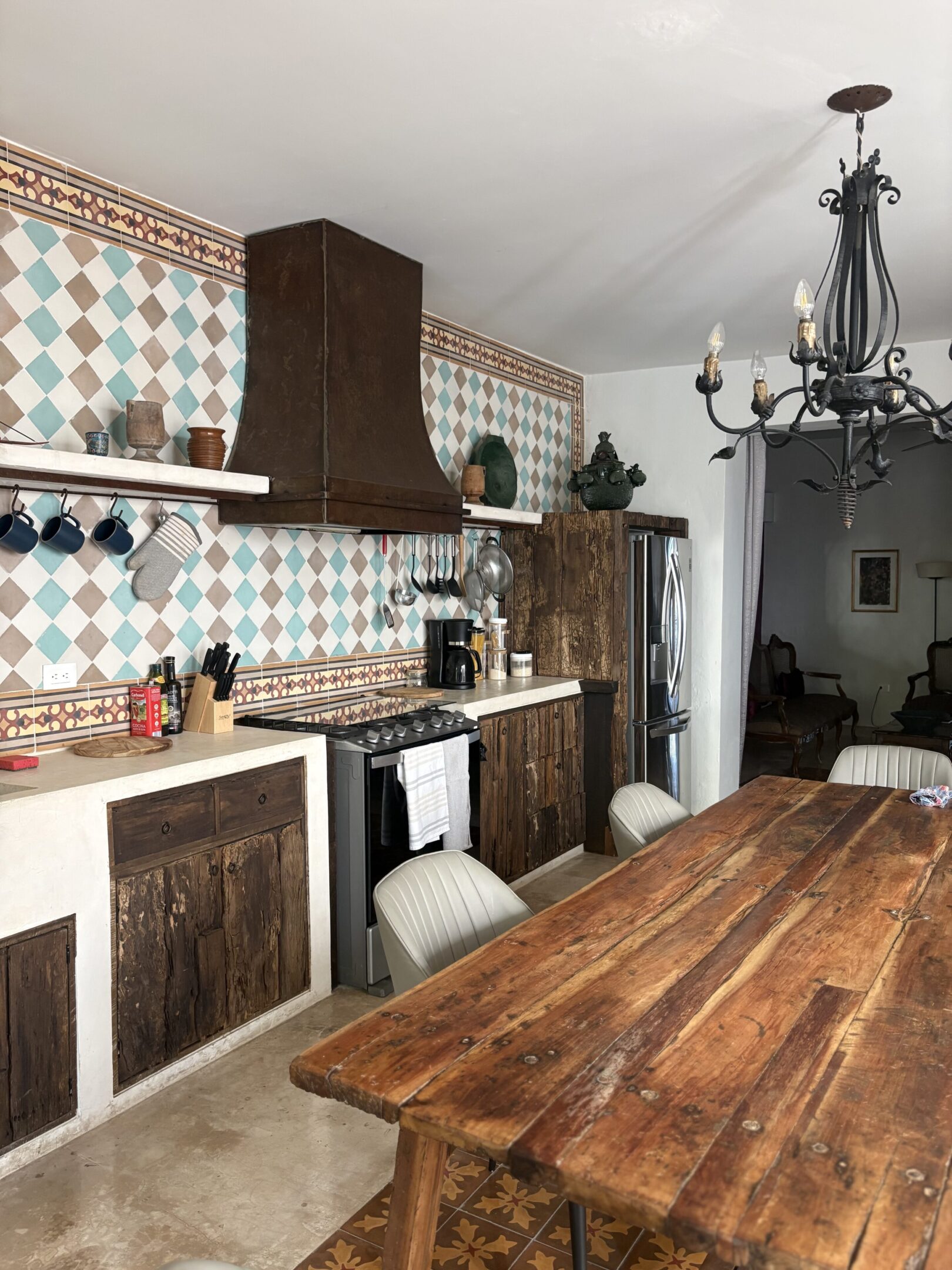 Rustic kitchen with wooden furniture and patterned tile backsplash.