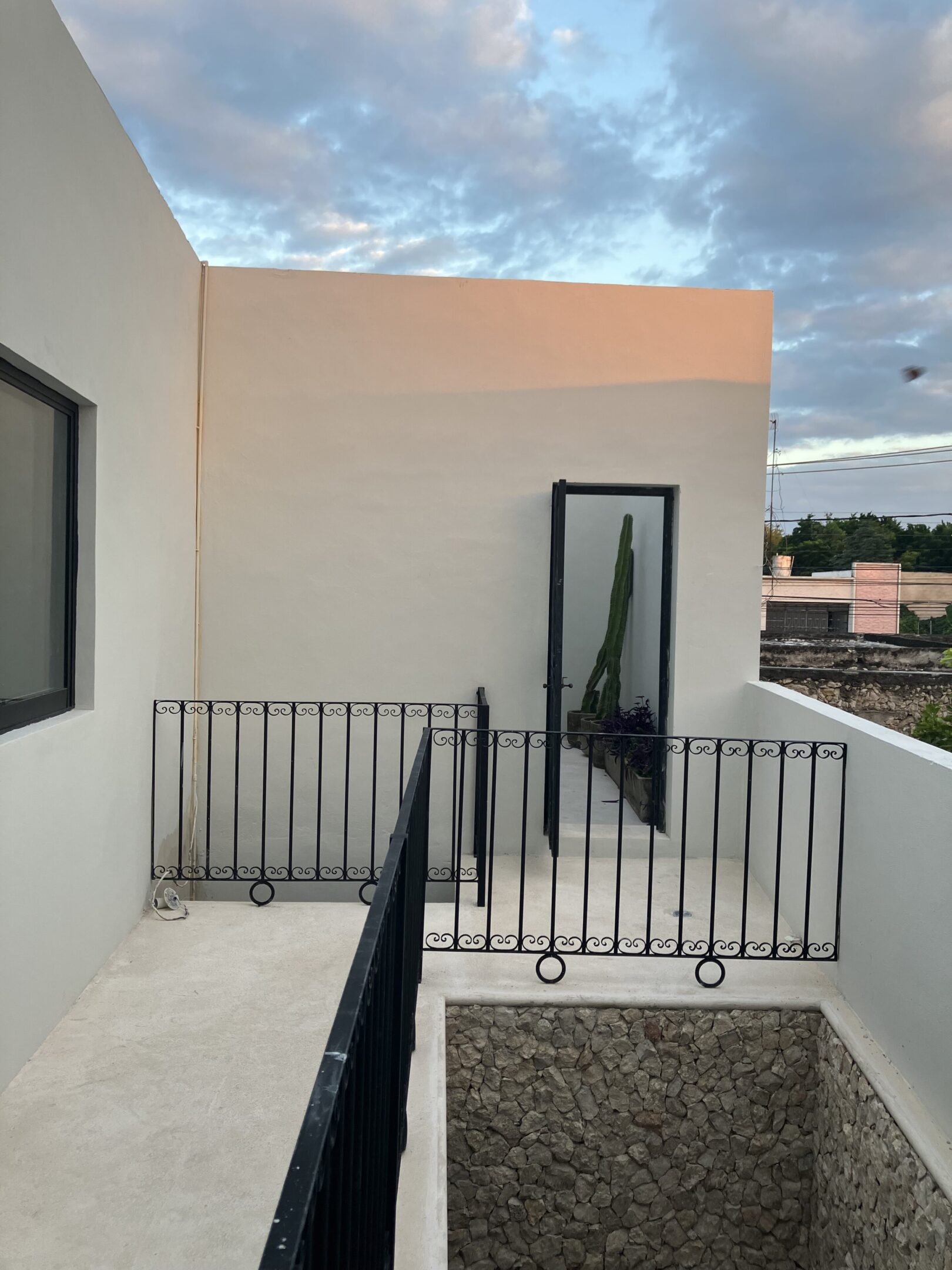 Narrow balcony with black railing and glass door on a modern building.