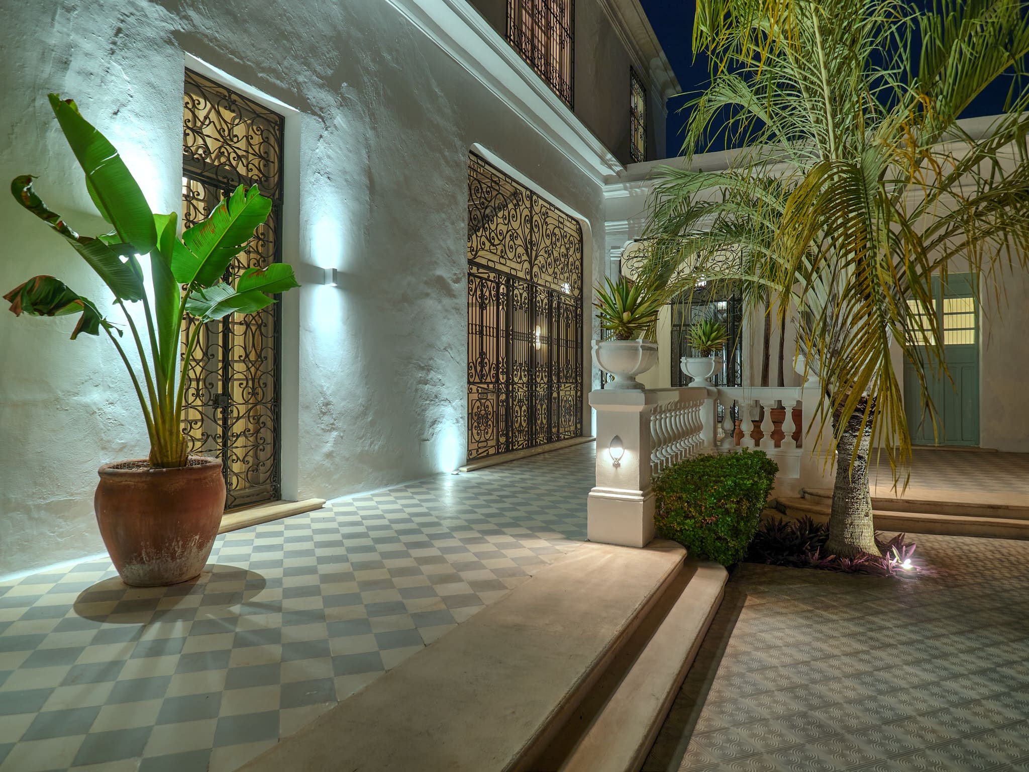 Elegant outdoor patio with palm plants and decorative lighting at night.