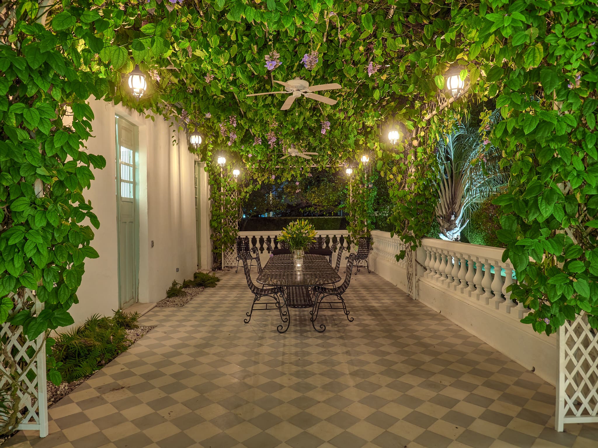 Cozy outdoor dining area with string lights and lush greenery.