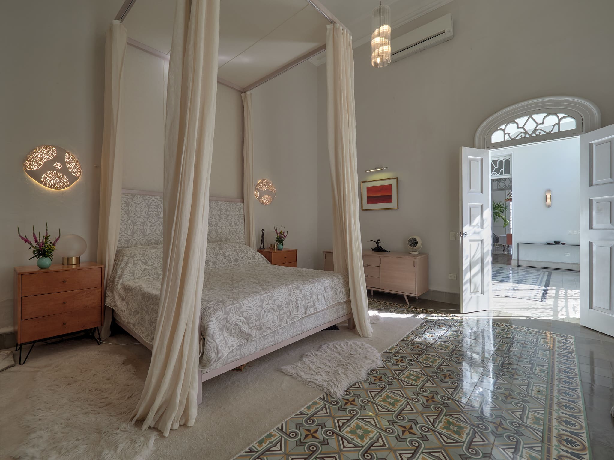 Elegant bedroom with a canopy bed and patterned floor tiles.