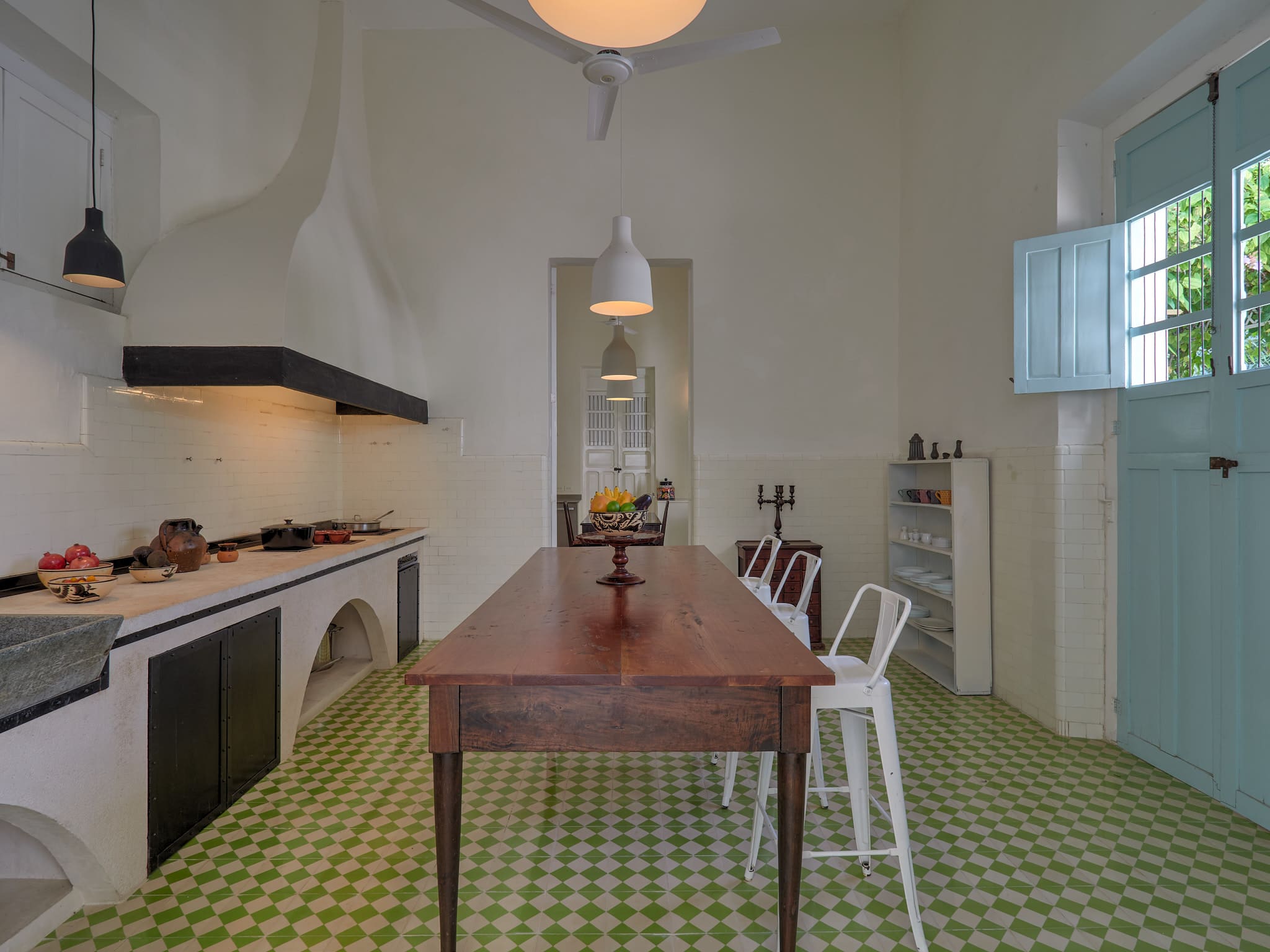 Modern kitchen with a wooden dining table and green tiled floor.