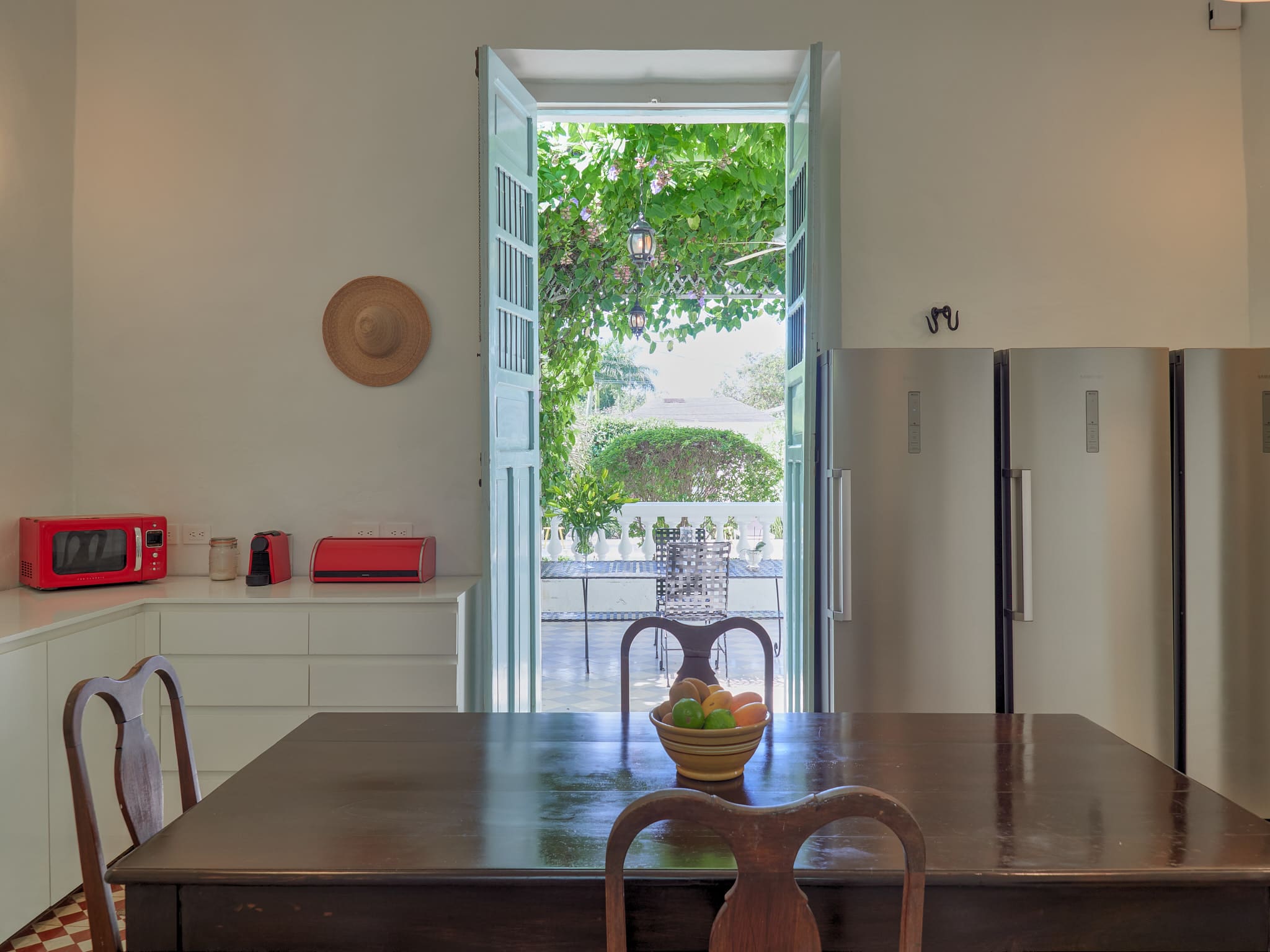 Open window overlooking green trees and outdoor seating area.