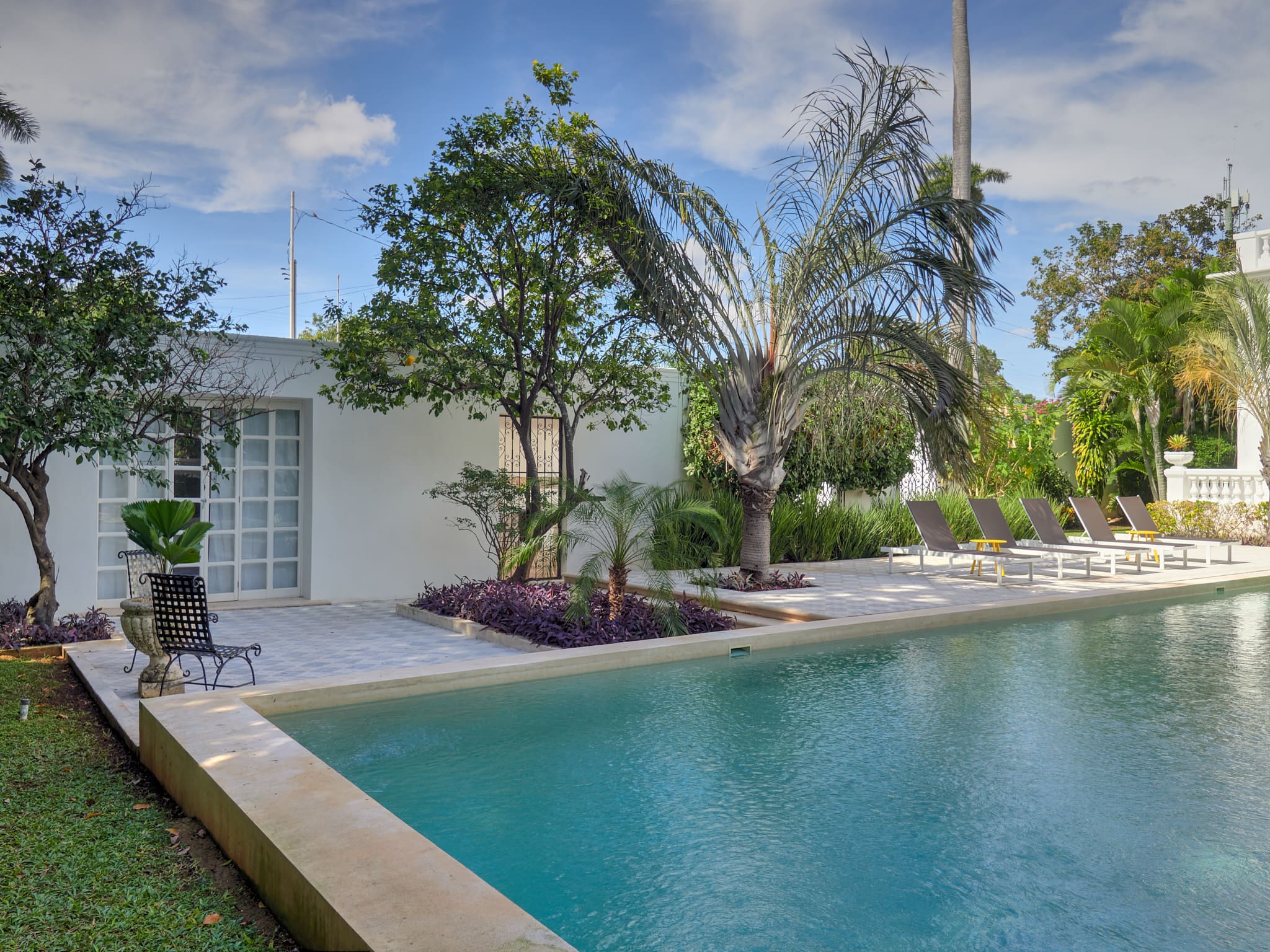 Tranquil backyard pool surrounded by lush greenery and patio furniture.