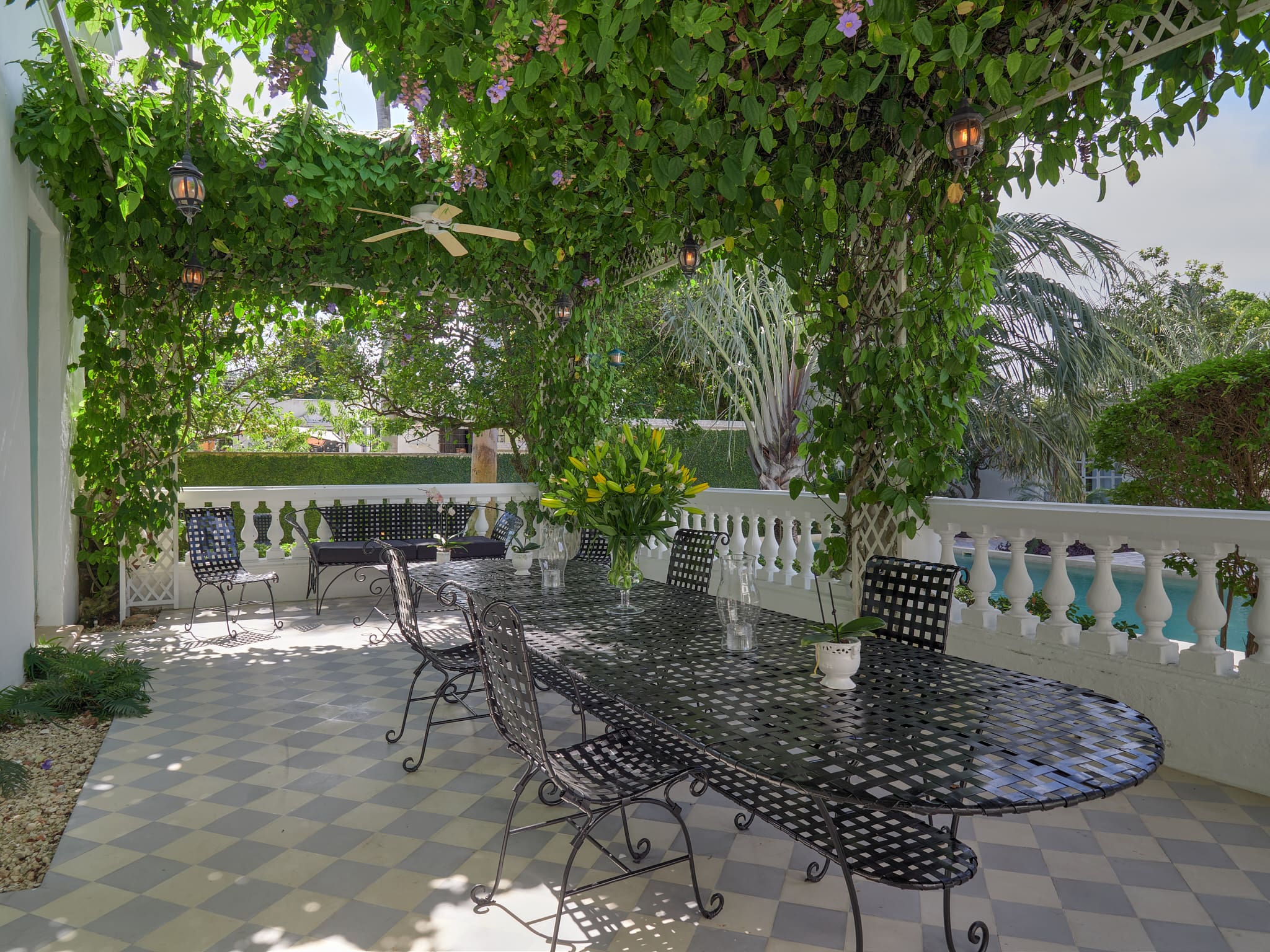 Elegant outdoor patio with wrought iron furniture under lush greenery.