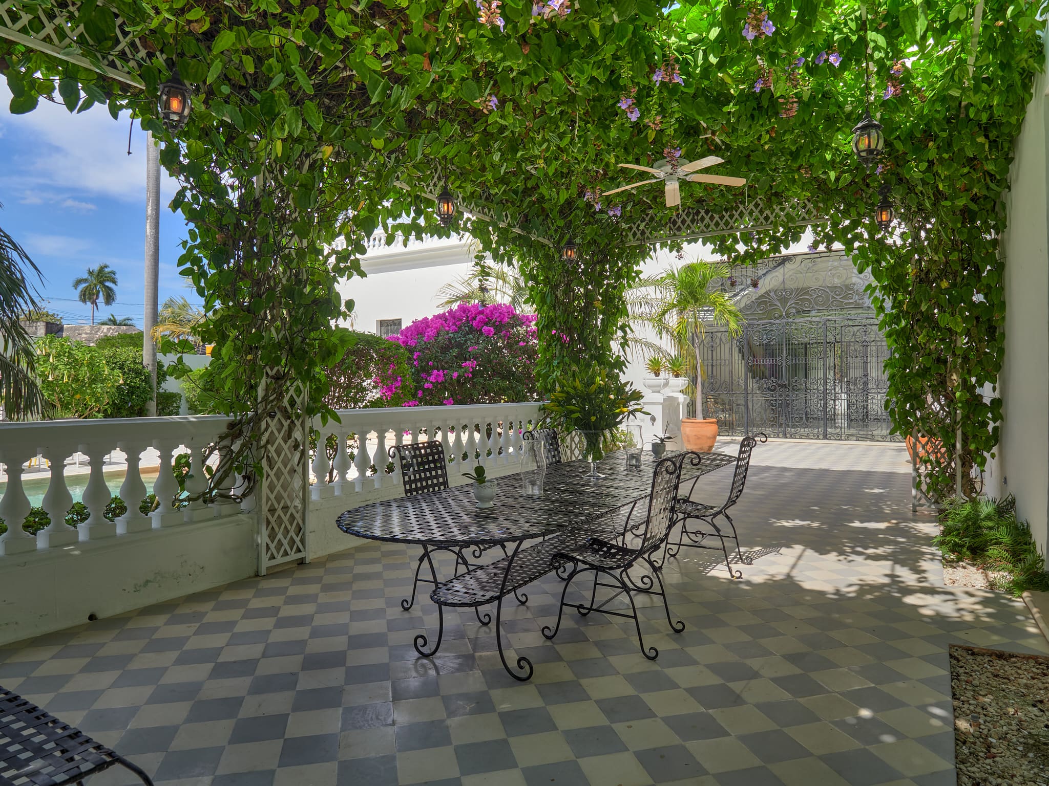 A serene outdoor patio with wrought iron furniture and lush greenery.