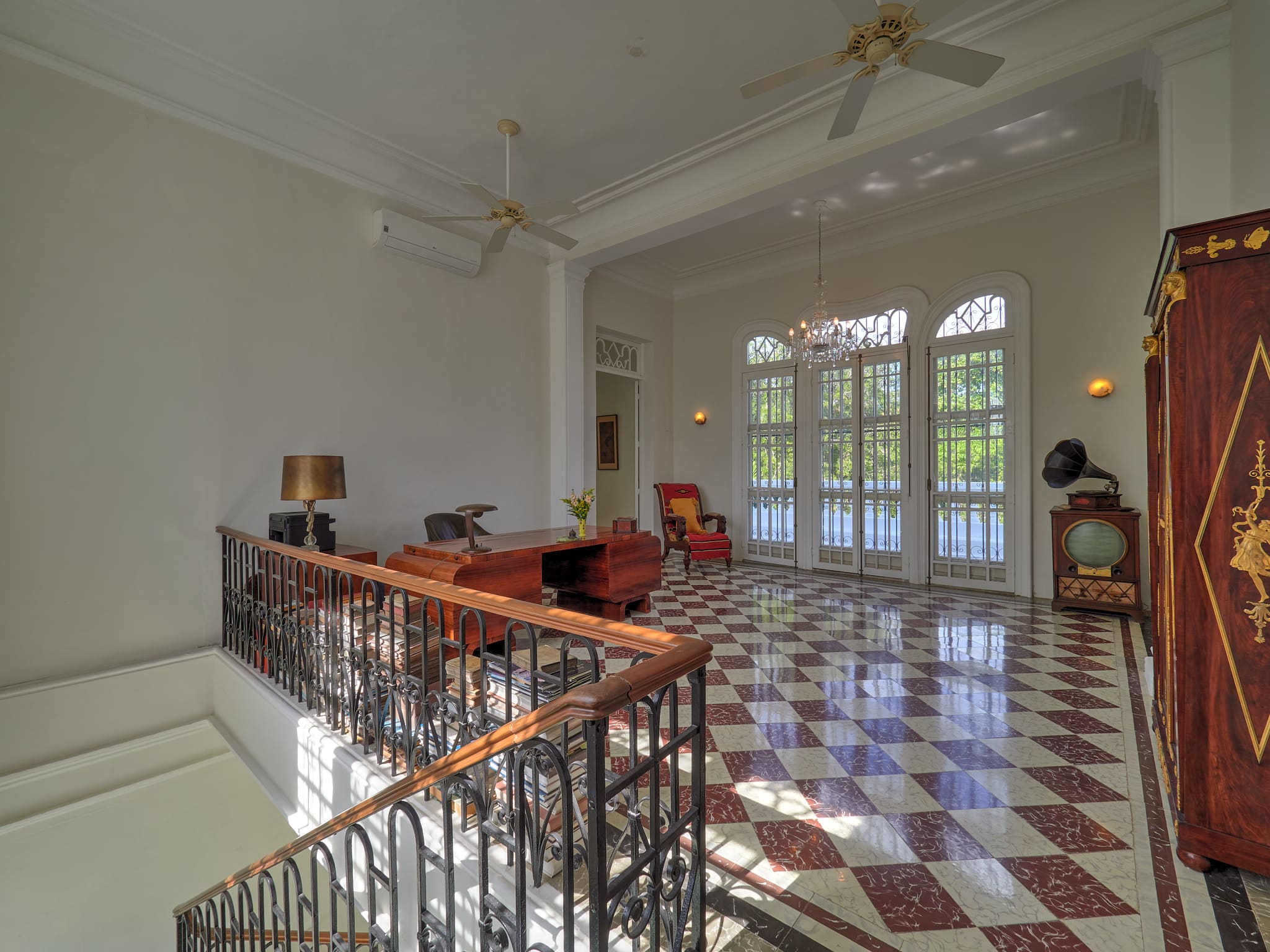 Spacious room with checkered floor, ceiling fans, and large windows.